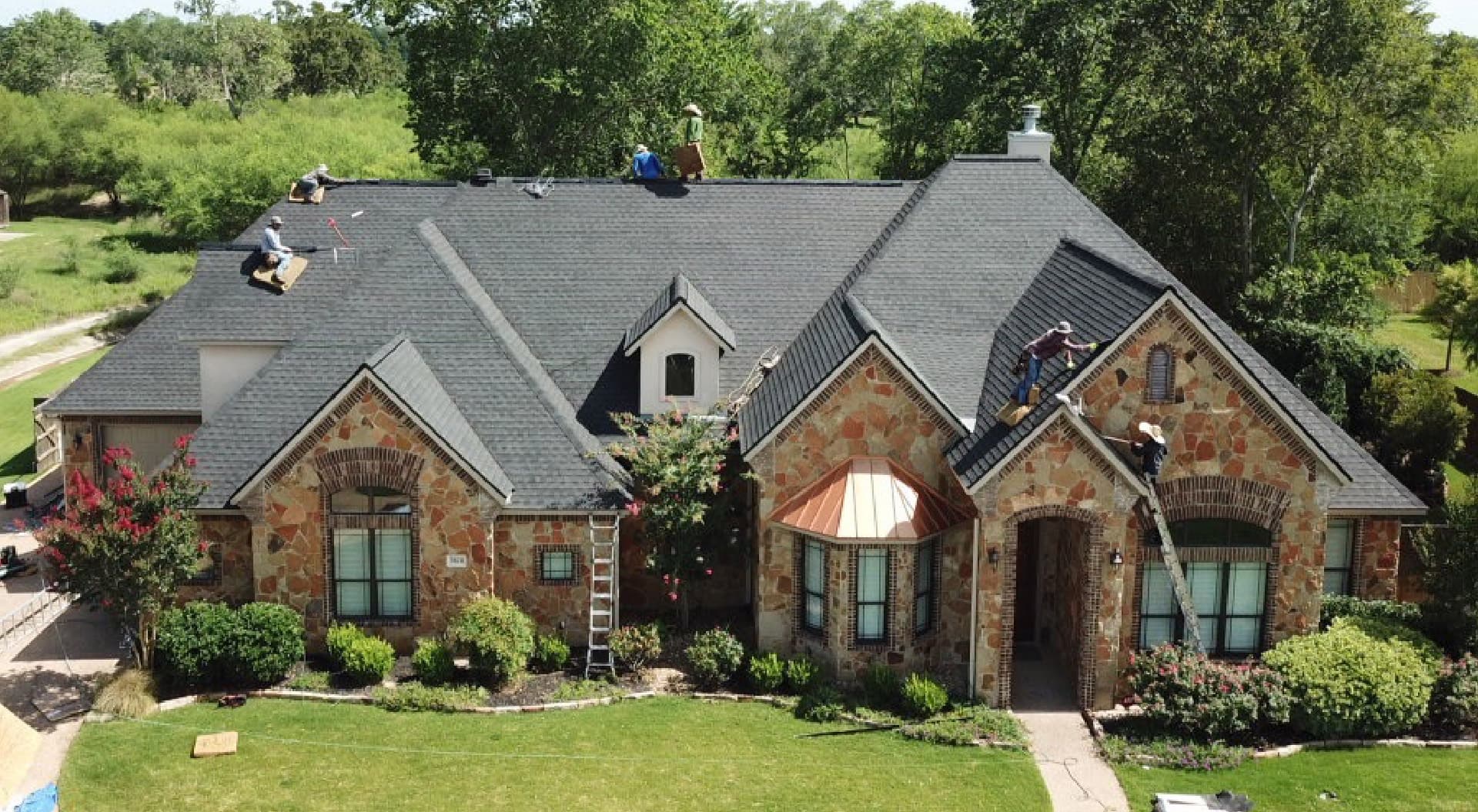 True Line Roofing crew replacing the shingle roof on a stone house in the Houston area